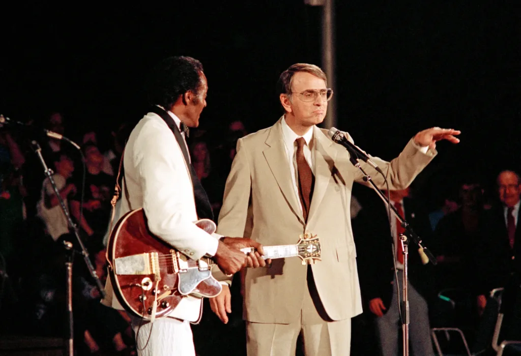 Chuck Berry with a guitar beside Carl Sagan at the Voyager 2 Neptune flyby celebration in August 1989