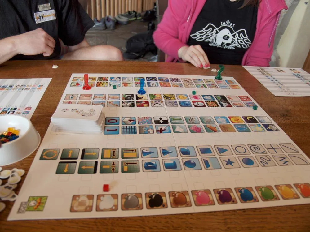 Players using coloured markers on the illustrated board of the game Concept