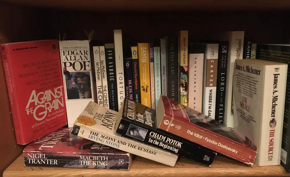 Books standing and leaning across a crowded shelf