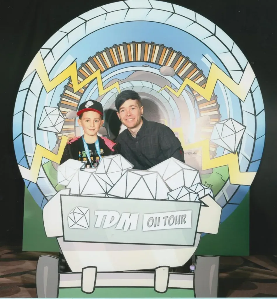 DanTDM posing with a fan beside his tour backdrop in November 2016
