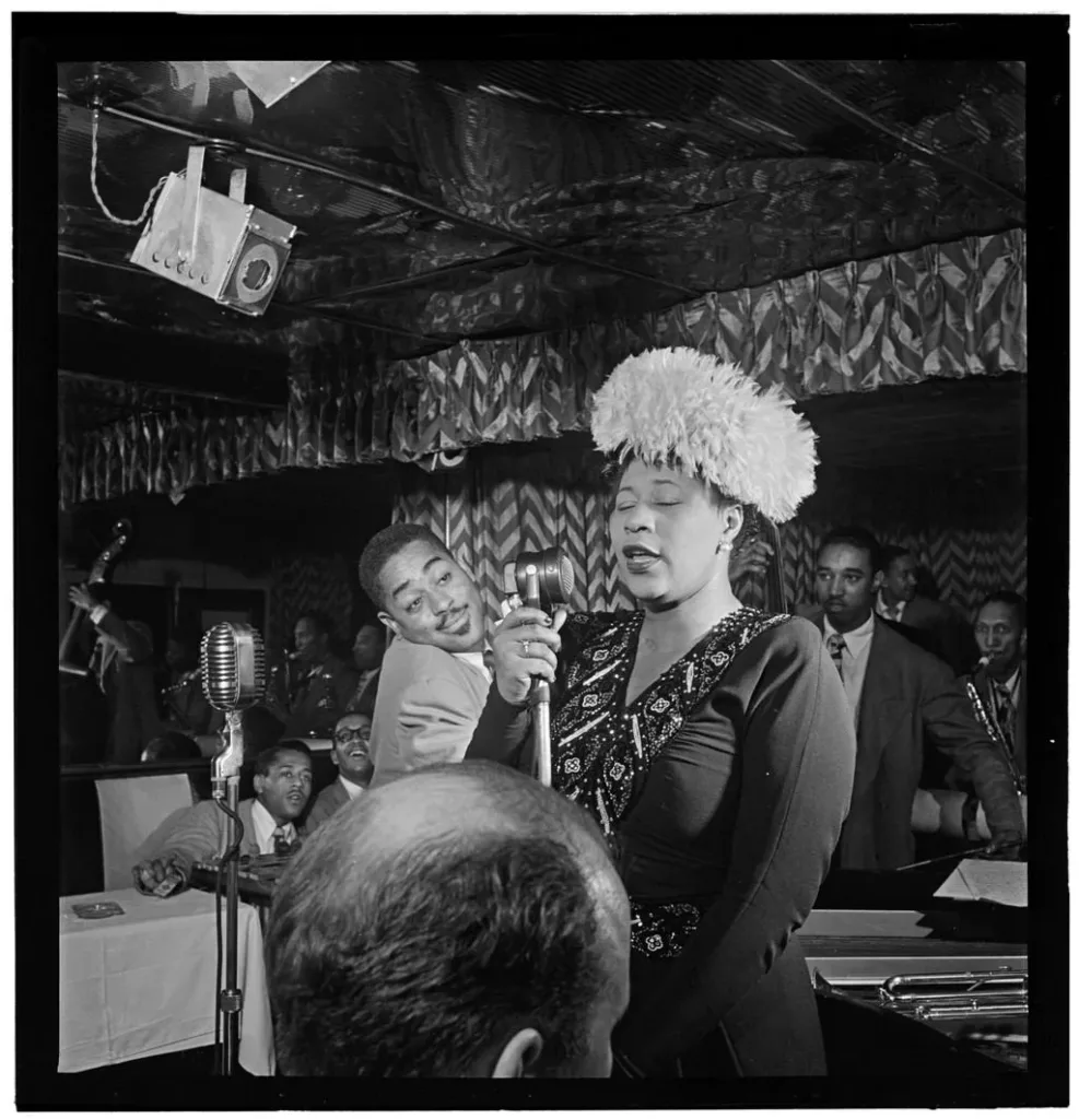Ella Fitzgerald singing at the Downbeat club with Dizzy Gillespie listening beside her in September 1947