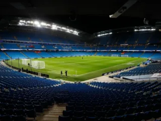 Wide view of the Etihad Stadium pitch and blue seating in Manchester