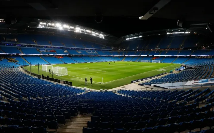Wide view of the Etihad Stadium pitch and blue seating in Manchester