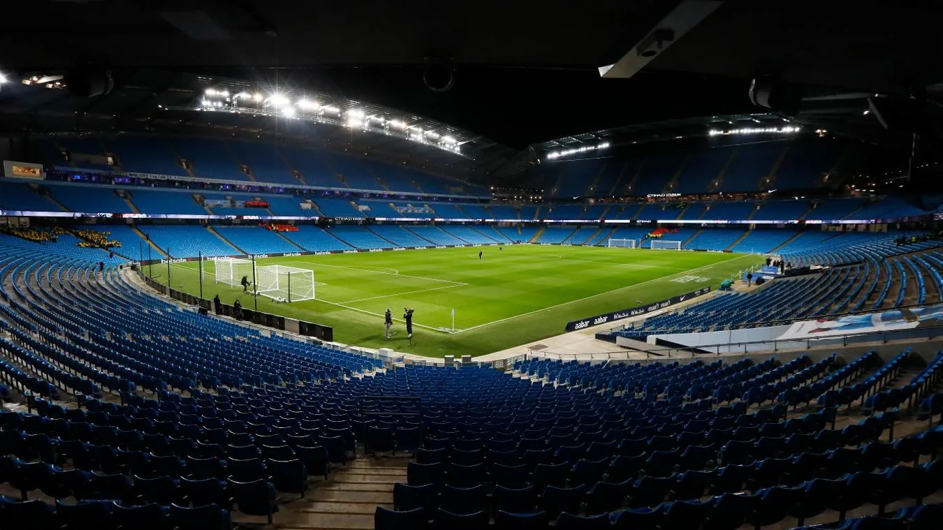 Wide view of the Etihad Stadium pitch and blue seating in Manchester