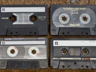 Four compact audio cassettes showing their labels and tape reels