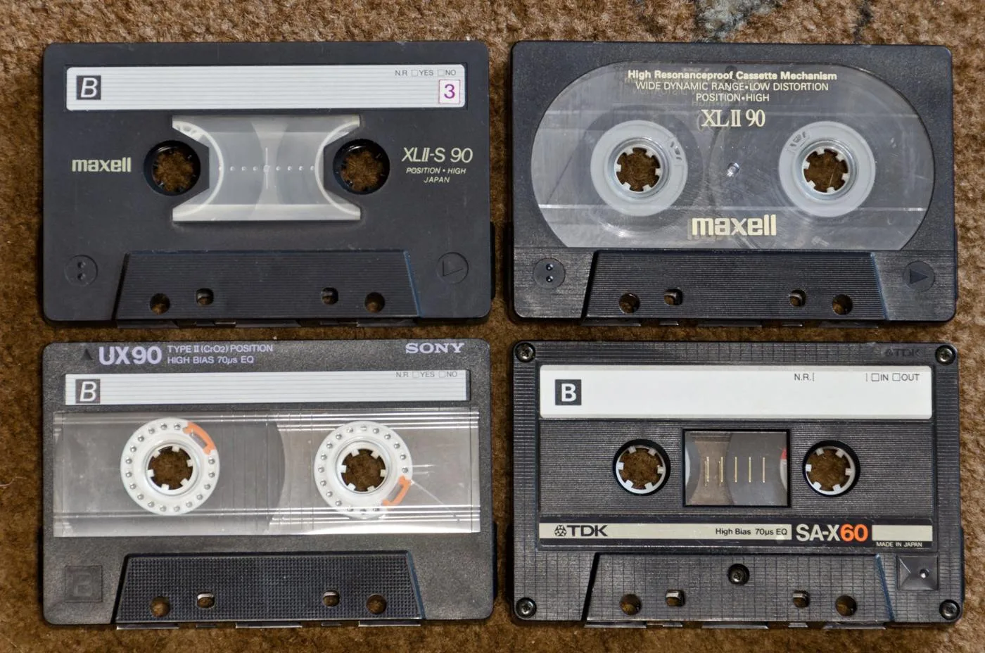 Four compact audio cassettes showing their labels and tape reels