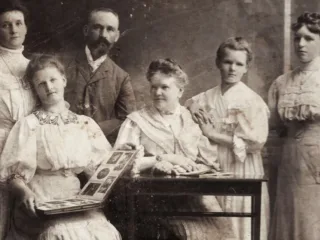A family posed with photograph albums in a historical image dated 1900