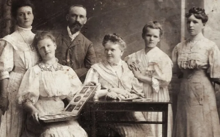 A family posed with photograph albums in a historical image dated 1900