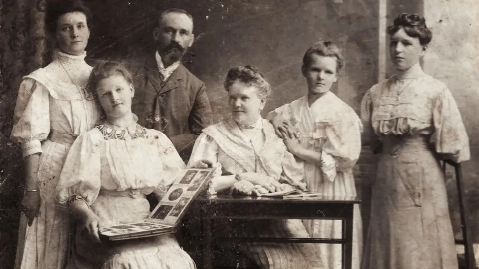 A family posed with photograph albums in a historical image dated 1900