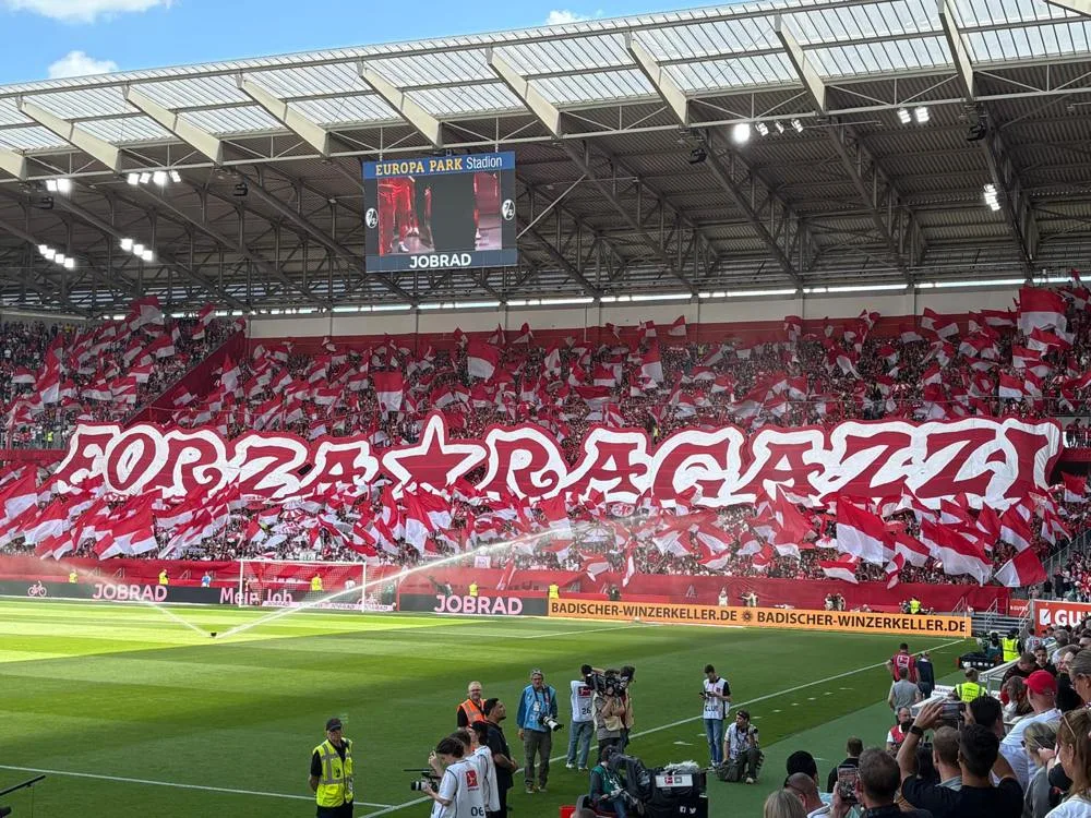 SC Freiburg supporters holding red and white flags at the Europa-Park Stadion in May 2025