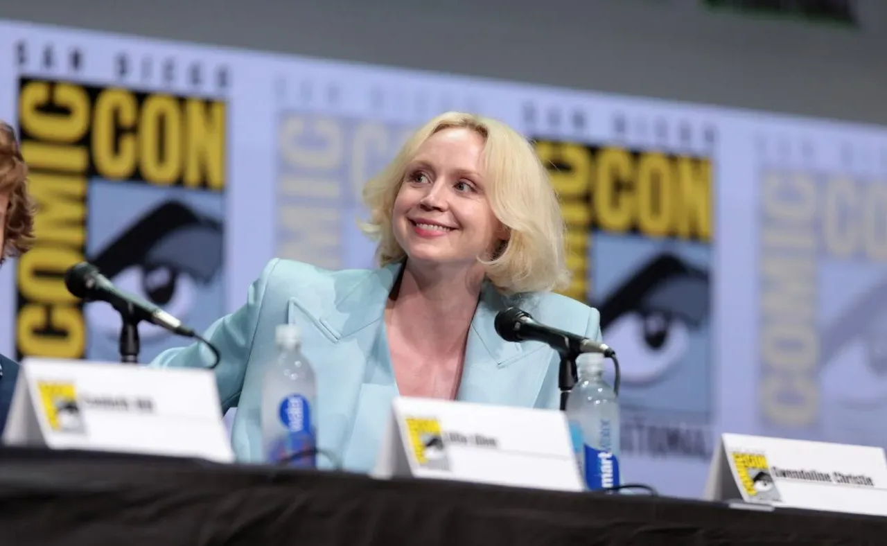 Gwendoline Christie seated at a Comic-Con panel in a pale blue jacket in 2017