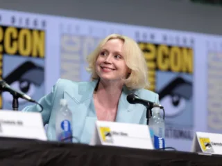 Gwendoline Christie seated at a Comic-Con panel in a pale blue jacket in 2017