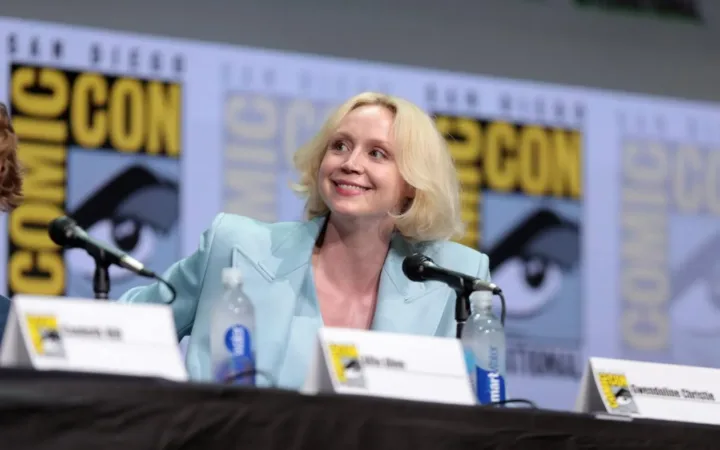 Gwendoline Christie seated at a Comic-Con panel in a pale blue jacket in 2017