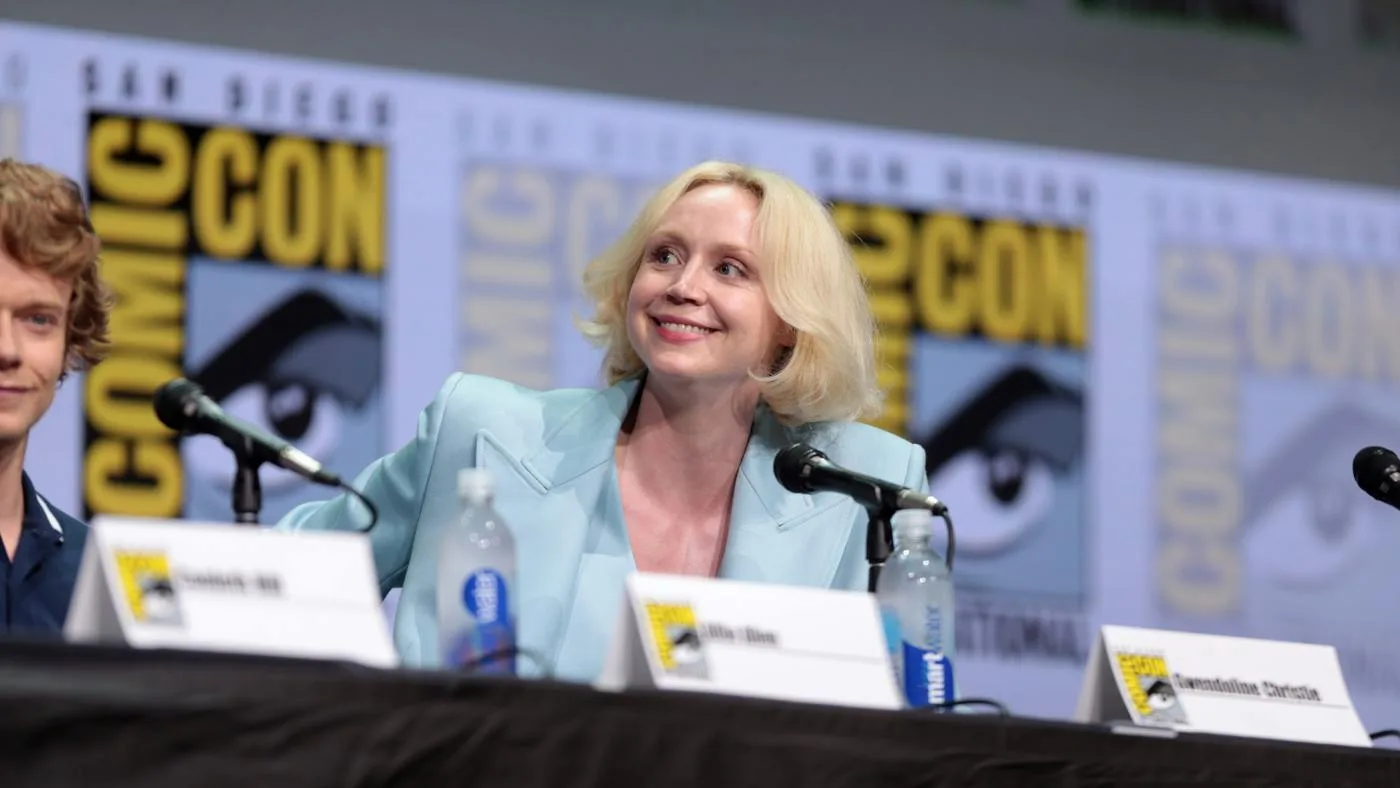 Gwendoline Christie seated at a Comic-Con panel in a pale blue jacket in 2017