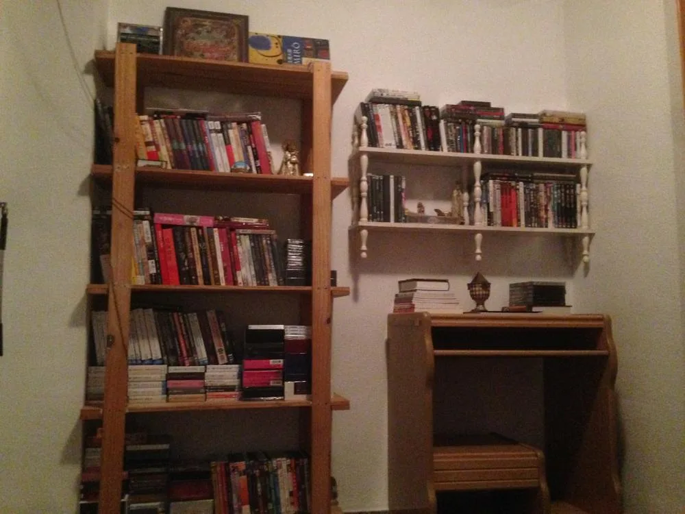 A tall bookcase and wall shelves holding books in a room