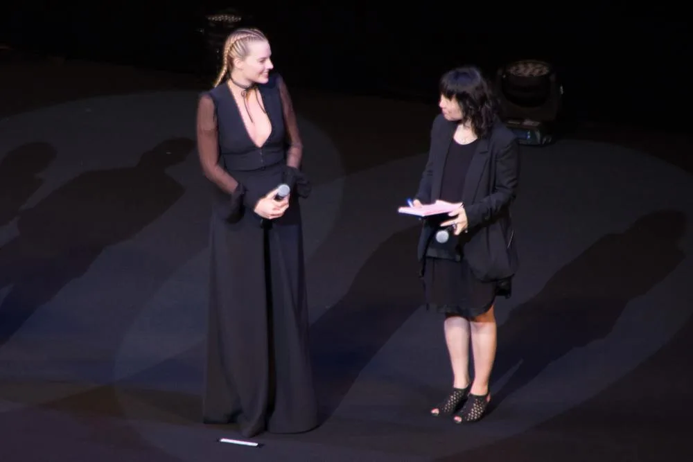 Margot Robbie stands with a microphone on stage at the 2016 Suicide Squad premiere in Japan.