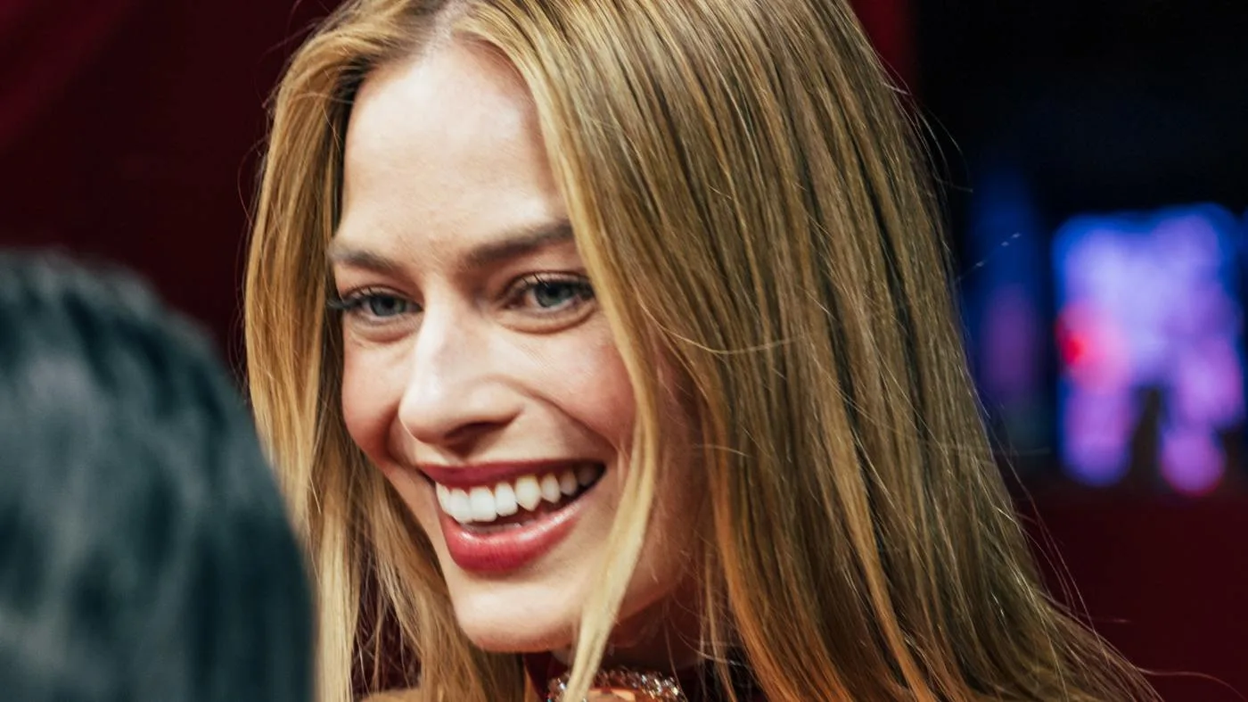 Open the featured image for Margot Robbie and Tom Ackerley: The Work Behind the Marriage Margot Robbie smiles at the Paris premiere of Wuthering Heights in February 2026.