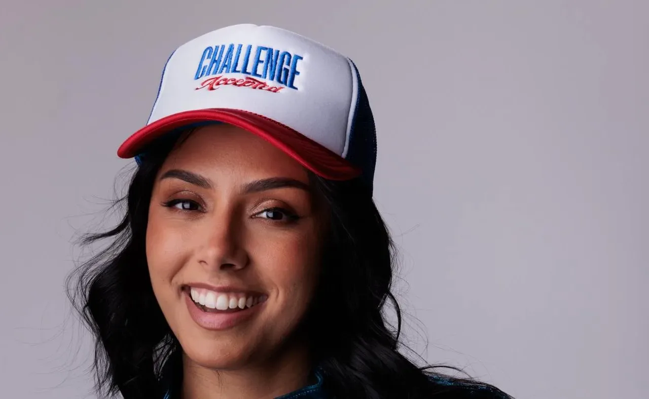 Michelle Khare wearing a Challenge Accepted cap and a blue jacket
