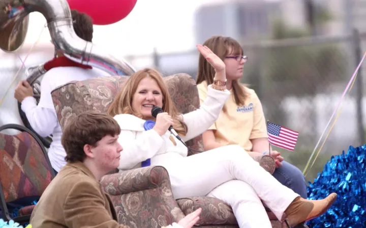 Nancy Cartwright waves while holding a microphone at the Phoenix Veterans Day parade in 2011