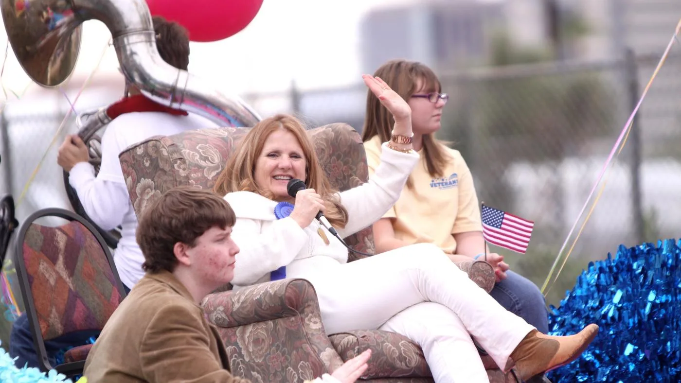 Open the featured image for Nancy Cartwright Net Worth: What Her Voice Career Reveals Nancy Cartwright waves while holding a microphone at the Phoenix Veterans Day parade in 2011
