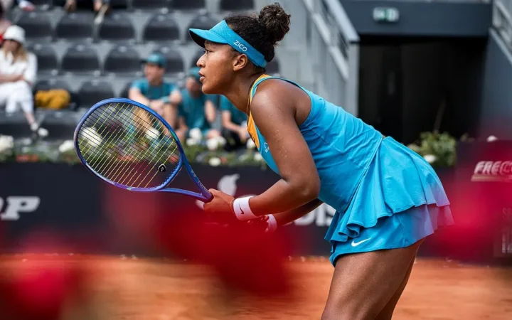 Naomi Osaka preparing to return a shot on a tennis court