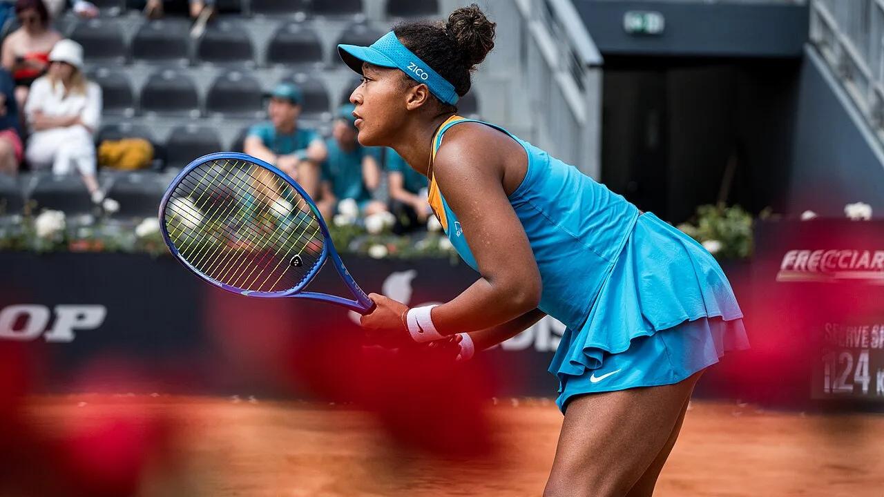 Naomi Osaka preparing to return a shot on a tennis court