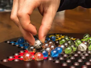 A player moving a glass marble during a board game night