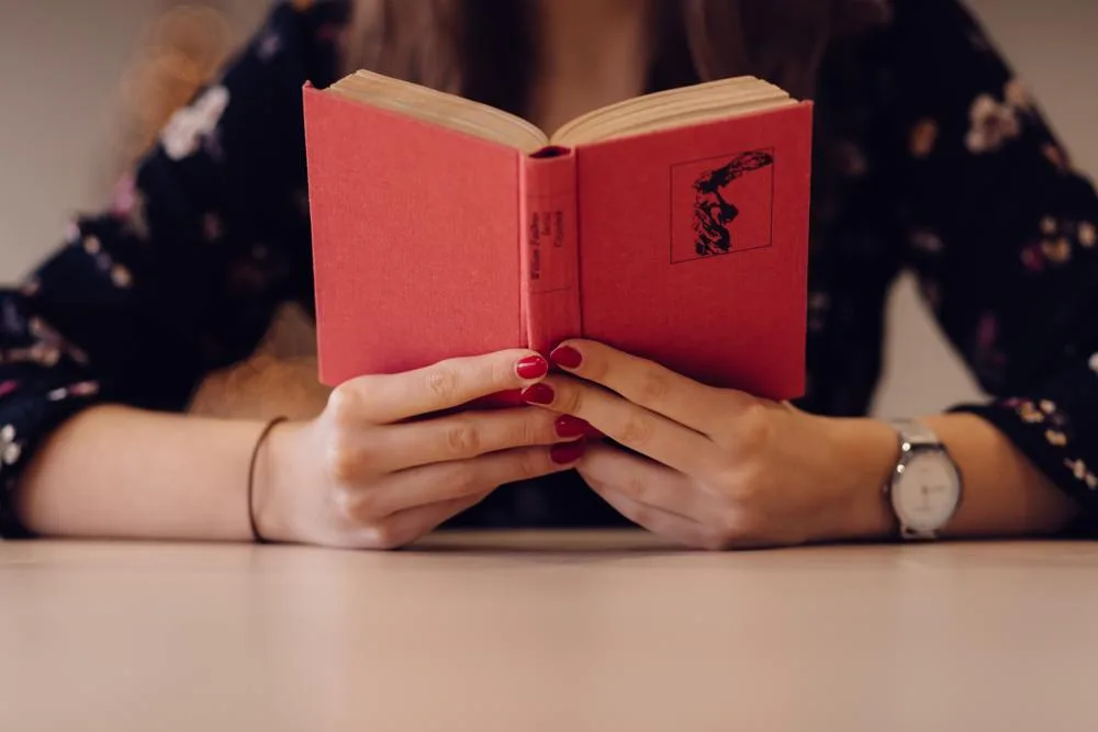 A reader holding an open red hardback book