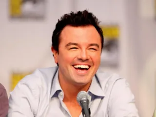 Seth MacFarlane smiles behind a panel microphone at San Diego Comic-Con in 2010.
