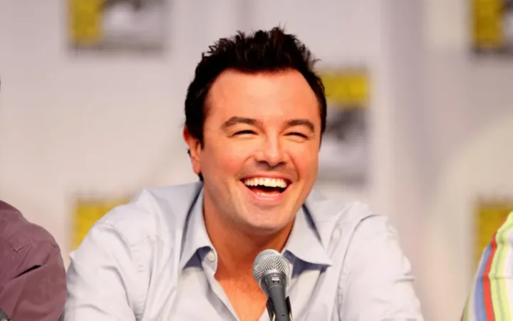 Seth MacFarlane smiles behind a panel microphone at San Diego Comic-Con in 2010.