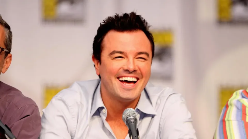 Seth MacFarlane smiles behind a panel microphone at San Diego Comic-Con in 2010.