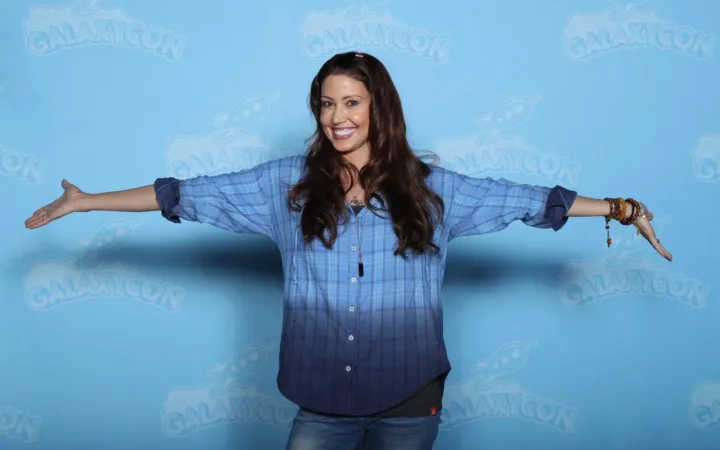 Shannon Elizabeth smiles in a blue plaid shirt at GalaxyCon in 2020