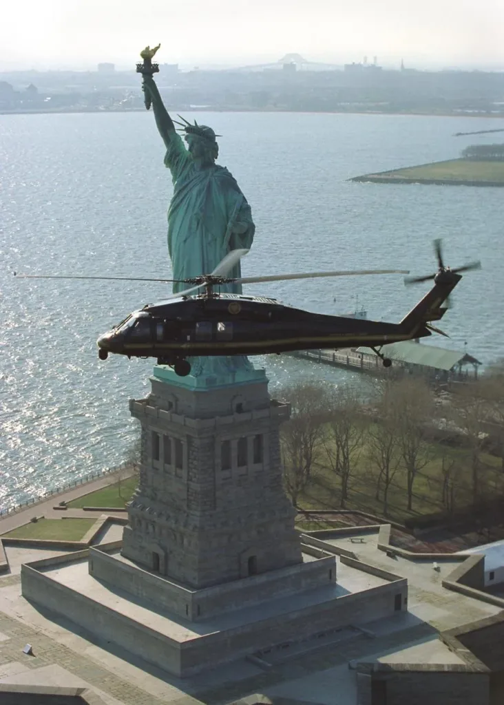 An archival view of the Statue of Liberty with a helicopter passing in front