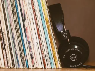A row of sleeved vinyl records with headphones resting alongside them