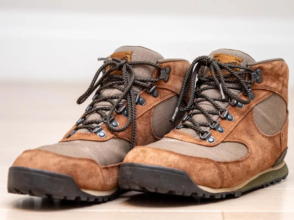 A pair of brown hiking boots with laces and textured soles.