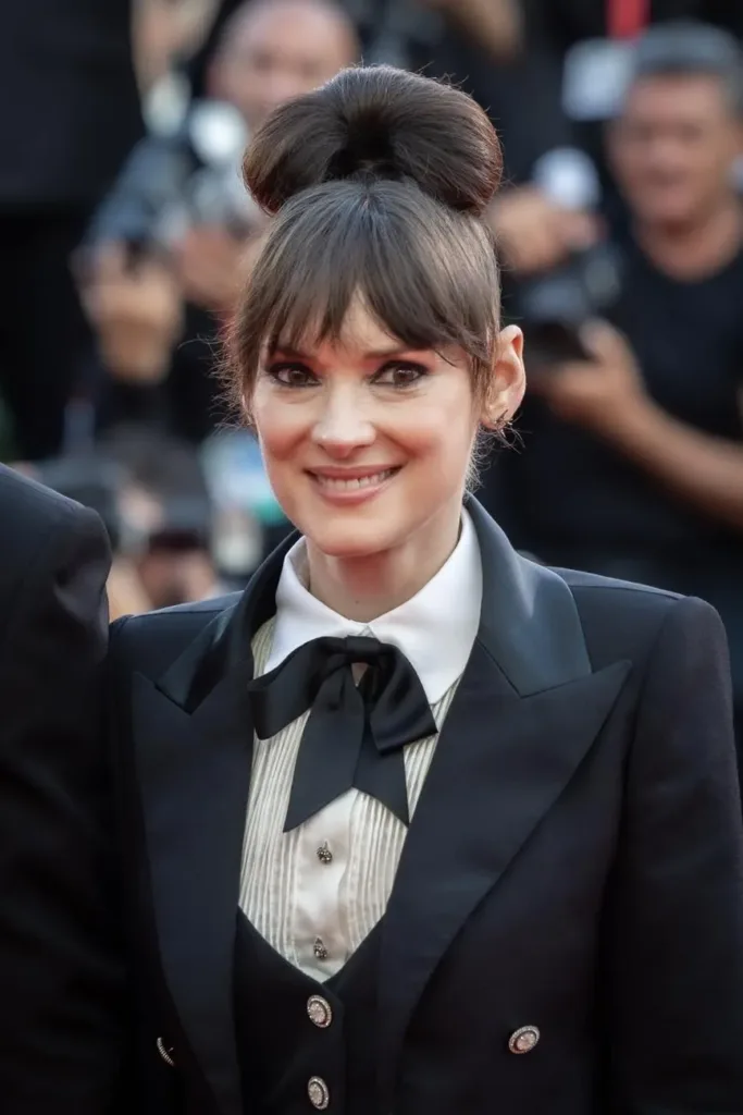 Winona Ryder wearing a dark suit and bow at Venice in August 2024