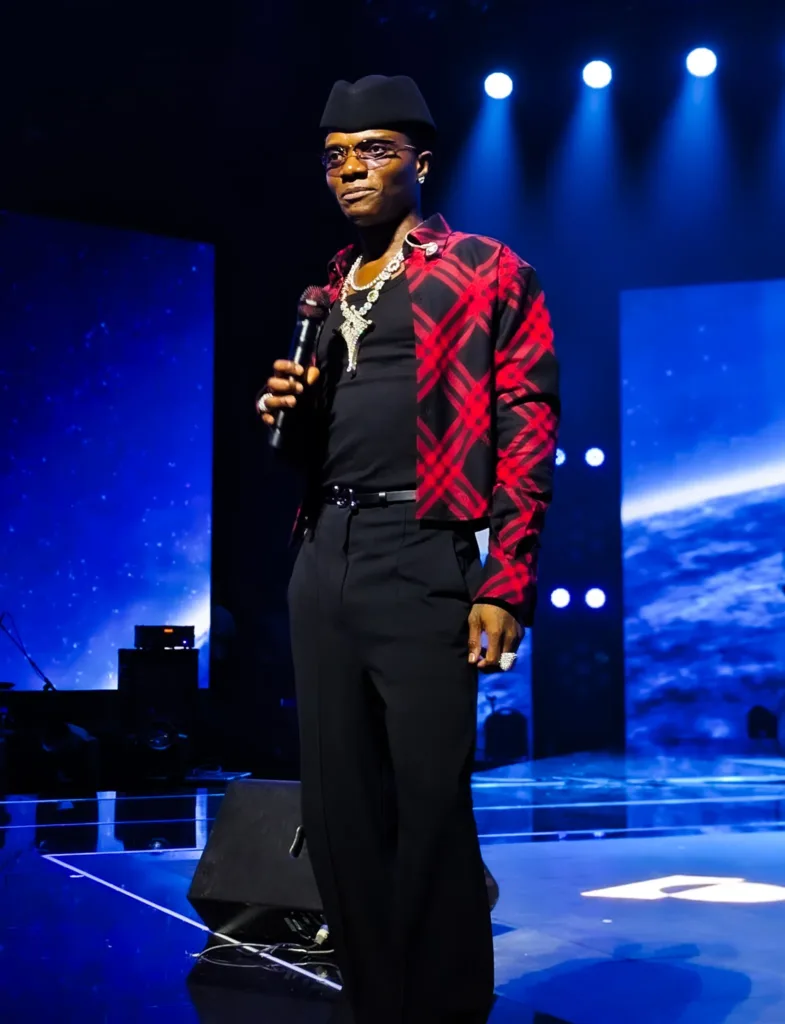 Wizkid holding a microphone at the CANEX mega concert in Algiers in 2025